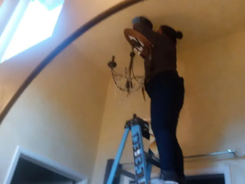 Electrician installing a chandelier in a Boston residence